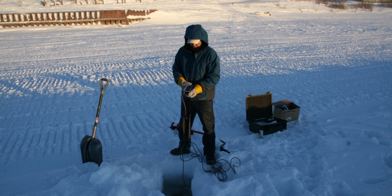A technician from ARI takes a measurement of salinity and temperature at the water monitoring site at the Inuvik town dock